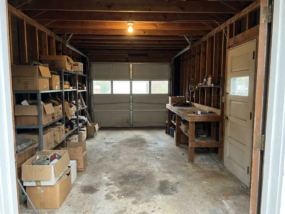 One-car garage restyled with wall shelving, a slatwall, and a folding workbench — before