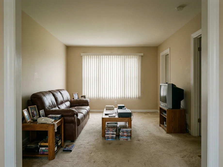 Living room restyled with a sectional, layered rug, and a media console — before