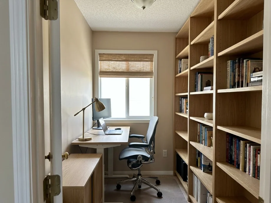 Home office upgraded with a sit-stand desk, a credenza, and a bookshelf wall. after AI redesign