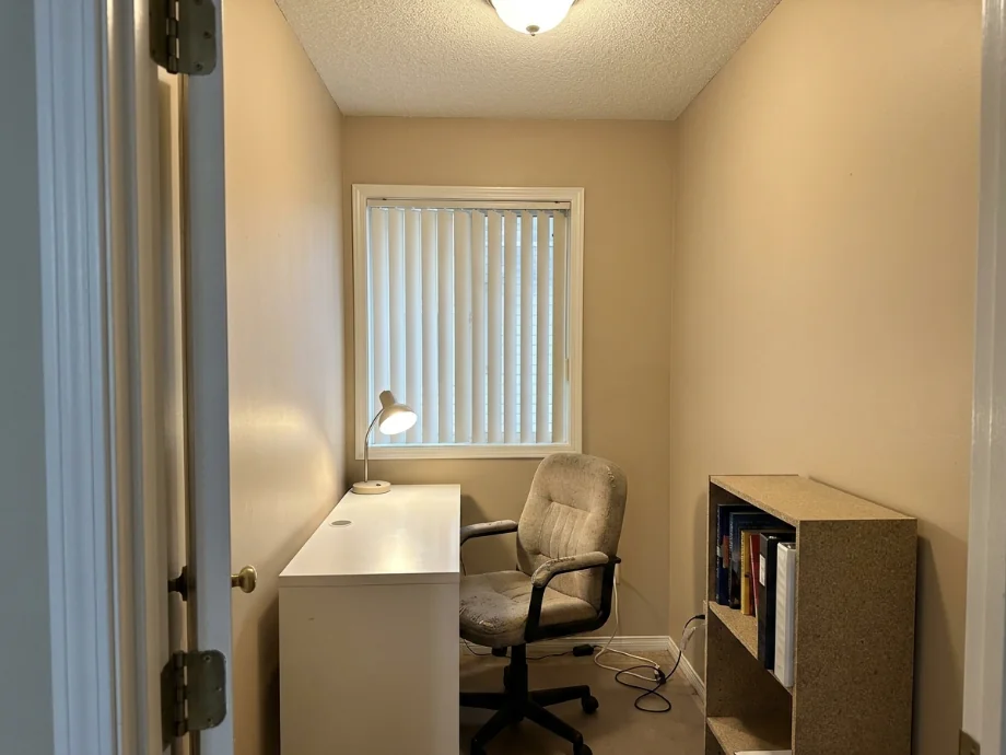 Home office upgraded with a sit-stand desk, a credenza, and a bookshelf wall. before AI redesign