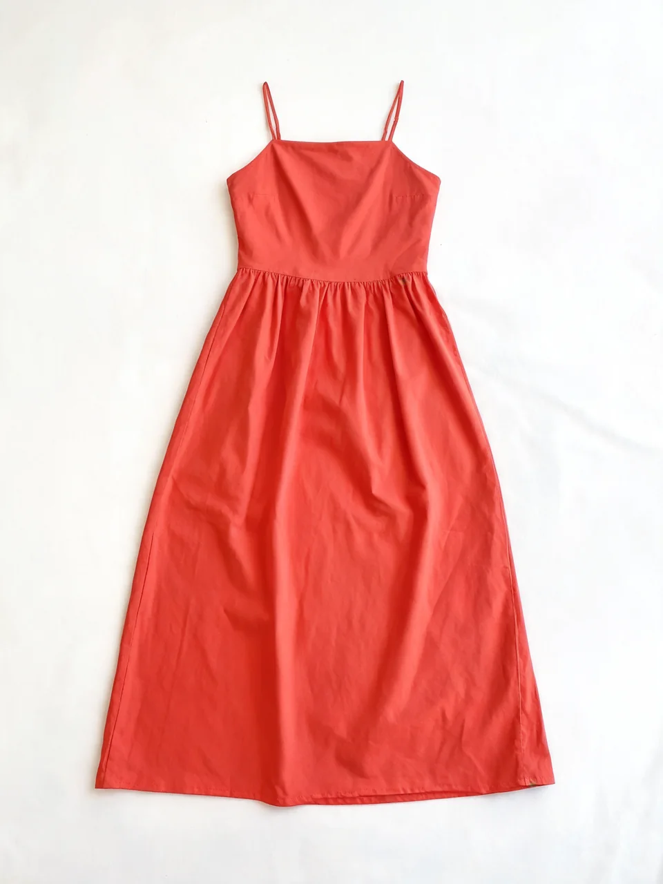 Coral red summer dress flat-lay turned into a photo of a fashion model wearing it before AI redesign