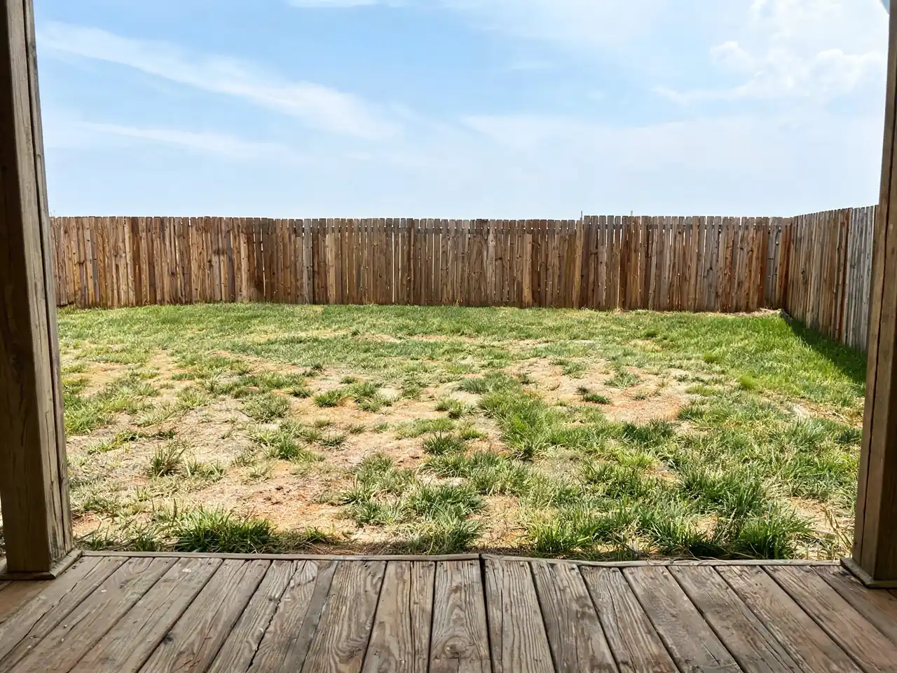 Garden studio placed at real scale against the existing fence โ the lawn and decking are untouched โ before